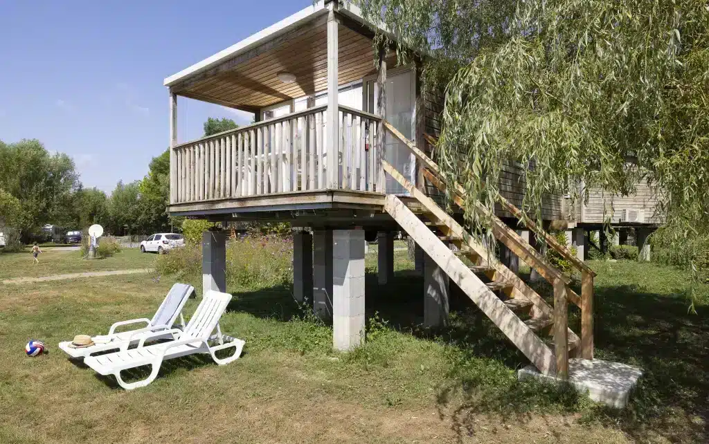 Cabane en bois surélevée avec chaises longues.