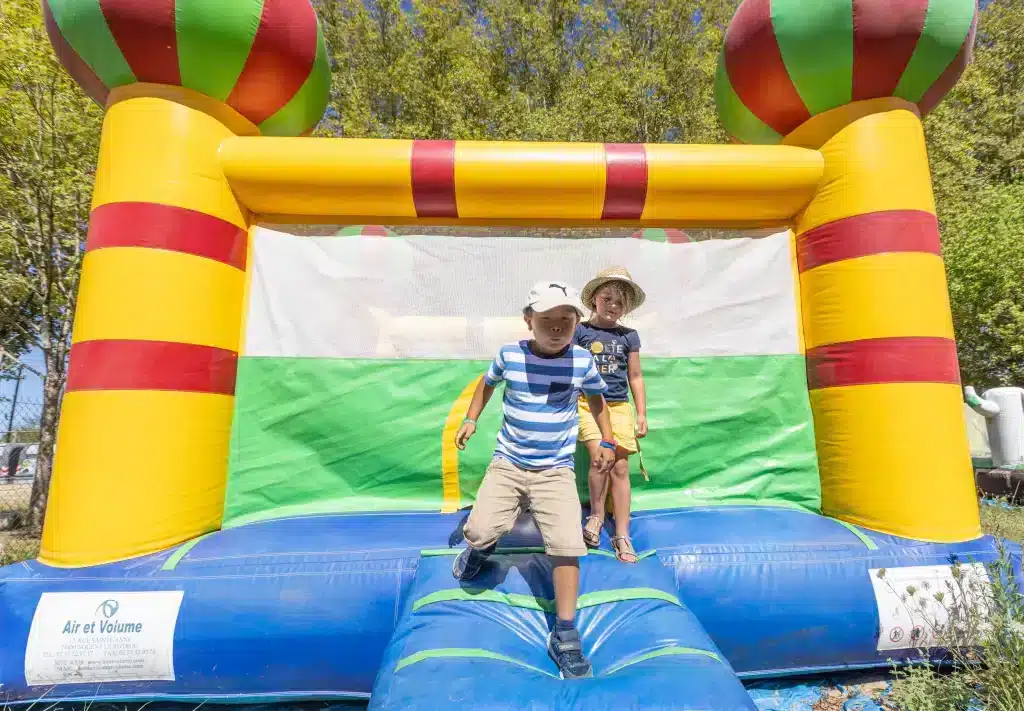Enfants jouant sur un château gonflable coloré.