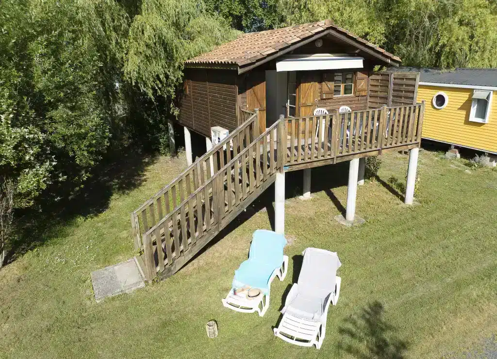 Chalet en bois avec terrasse et transats extérieurs.