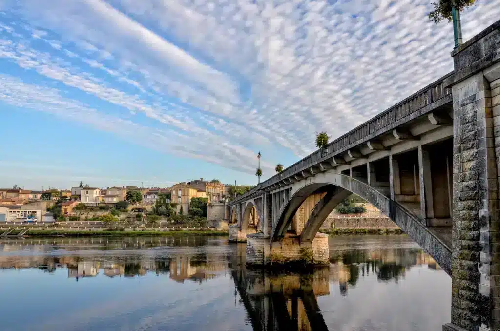 Pont historique au-dessus d'une rivière avec ciel bleu.